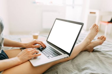 Kız evde, kanepede dizüstü bilgisayarla çalışıyor. Kız evde çalışıyor, yatakta yatıyor. Karantina sırasında çevrimiçi kazanç. 