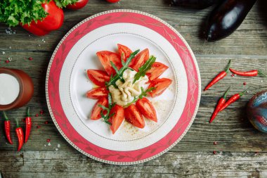 Ahşap arka planda sebze dekoru olan restoran yemeği. Tabakta domatesli Mozzarella peyniri 