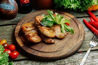 Ahşap arka planda sebze dekoru olan restoran yemeği. Soslu tütün tavuğu ve tabakta otlar.. 