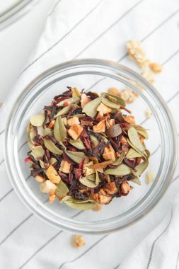 Beyaz arka planda meyveli doğal yeşil çay. Bardak tabağında meyve çayı yaprakları. 