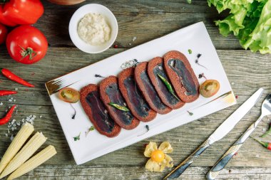 Ahşap arka planda sebzeli restoran yemeği. Dilimlenmiş baharatlı Azerbaycan basturma. 