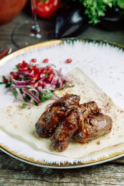  Ahşap arka planda sebzeli restoran yemeği. Azerbaycan domuz böbreği ve soğanlı pide ekmeği.