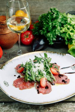  Ahşap arka planda sebzeli restoran yemeği. Biftek filetosu ve roka tabağında salata..