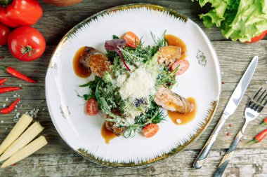  Ahşap arka planda sebzeli restoran yemeği. Biftek filetosu ve roka tabağında salata..