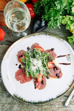  Ahşap arka planda sebzeli restoran yemeği. Biftek filetosu ve roka tabağında salata..