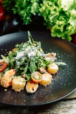  Ahşap arka planda sebzeli restoran yemeği. Karidesli salata, avokado ve roka..