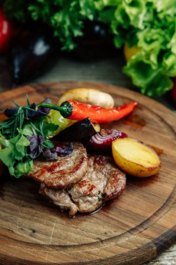 Ahşap arka planda sebzeli restoran yemeği. Tahta üzerinde sebzeli ve biberli biftek.. 