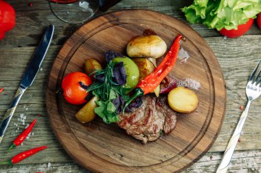 Ahşap arka planda sebzeli restoran yemeği. Tahta üzerinde sebzeli ve biberli biftek.. 