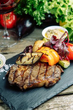 Ahşap arka planda sebzeli restoran yemeği. Biberli ve sebzeli kaburga bifteği.. 