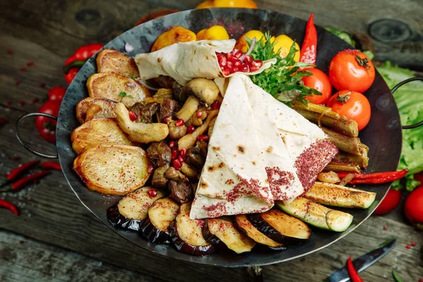 Ahşap arka planda restoran yemeği. Azerbaycan saj et ve sebzeli.