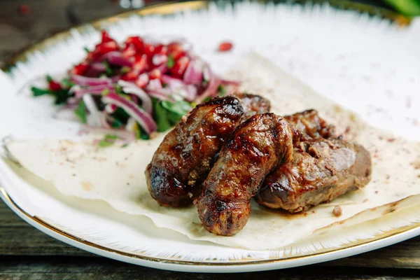 Restaurant dish on a wooden background with vegetables. Azerbaijani pork kidneys with onions on pita bread. — Stock Image Restaurant Dish Wooden Background Vegetables Azerbaijani Pork Kidneys Onions Pita Stock Picture