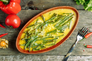 Ahşap arka planda sebzeli Azerbaycan restoranı yemeği. Kil tabakta çiğ yumurtalı fasulye.. 
