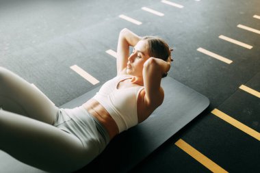 Spor salonunda egzersiz yapan bir kız. Siyah bir yüzeye uzanıyor. Matt 'ta basın eğitimi. 