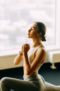 Flexibility exercises on a black background. Stretching in a dark room on a rug. Beautiful girl athlete on the floor. 