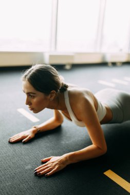 Flexibility exercises on a black background. Stretching in a dark room on a rug. Beautiful girl athlete on the floor. 