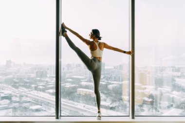  Stretching in the white room by the window. Beautiful girl athlete on the Mat. Flexibility exercises on a light background.