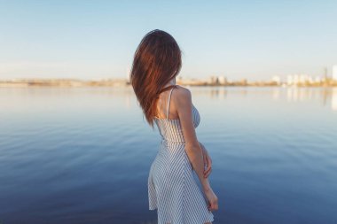 Summer Sunny sahil boyunca yürüyor. Gün batımında iskelede duygusal güzel bir kız.. 