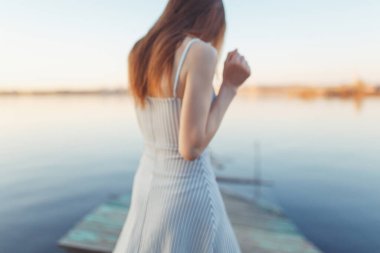 Summer Sunny sahil boyunca yürüyor. Gün batımında iskelede duygusal güzel bir kız.. 