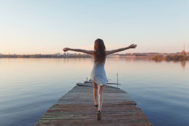 Summer Sunny sahil boyunca yürüyor. Gün batımında iskelede duygusal güzel bir kız.. 