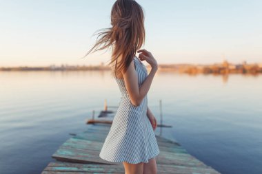 Summer Sunny sahil boyunca yürüyor. Gün batımında iskelede duygusal güzel bir kız.. 