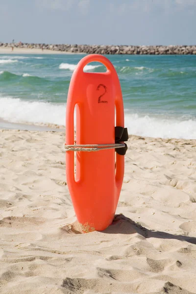 Bouée de sauvetage rouge dans le sable sur la plage — Photo