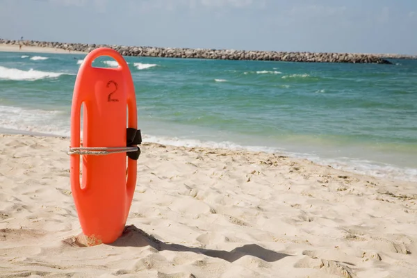 Bouée de sauvetage rouge dans le sable sur la plage — Photo