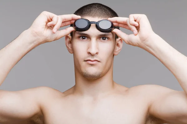 Young swimmer adjusts his goggles