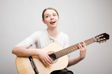 Bir gitar ile genç bir kız bir şarkı söyler