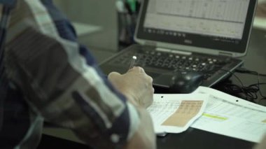 Gözlüklü adam dizüstü bilgisayarını düzeltiyor.