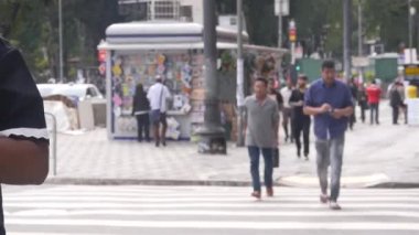 Siyah çantalı Asyalı adam karşıya geçiyor.