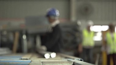 Mavi şapkalı fabrika işçisi 2 çelik çubuğu paten üzerinde itiyor.