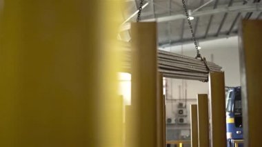 Fabrika işçisi, Crane 'in çelik çubukları taşımasına yardım ediyor.