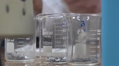 3 Kimyasal Ölçme Kadehi ve Arkada Düşüren Çocuk Elleri