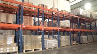 Bir depoda turuncu ve mavi raflar Sağdan Sola