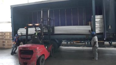 Kırmızı Çatal Asansörü Mavi Kamyonda Gürültülü Borular Yüklüyor.