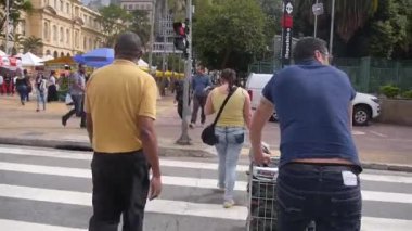 Mavi gömlekli adam caddenin karşısına Trolley 'i itiyor.