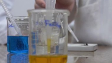 2 Kimyasal Ölçüm kabı mavi ve sarı sıvılar çocukların elleri arkada - odaklan