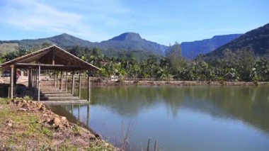 Kanyonlardaki yeşil bir gölün yanında bambu kulübeler.