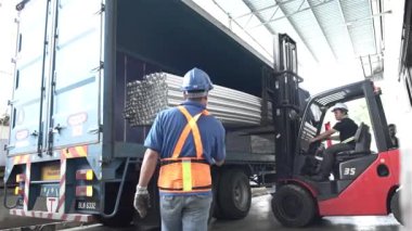 Kırmızı Çatal Asansörü Mavi Kamyonda Gürültülü Borular Yüklüyor