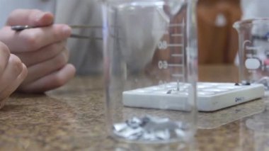 1 Kimyasal Ölçme Kadehi, çocukların elleri arkada.