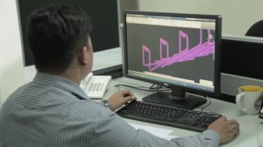 Striptiz tişörtlü adam, ofisteki mühendislik tasarımı üzerinde çalışıyor.