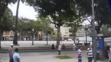 İnsanlar ve otobüsler tarafından hızla geçiliyor, otobüs kazandıktan sonra meydanın yakınından, sağdan sola kayıyor.