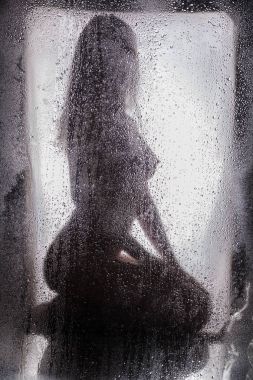 Islak bir cam arkasında çıplak kız