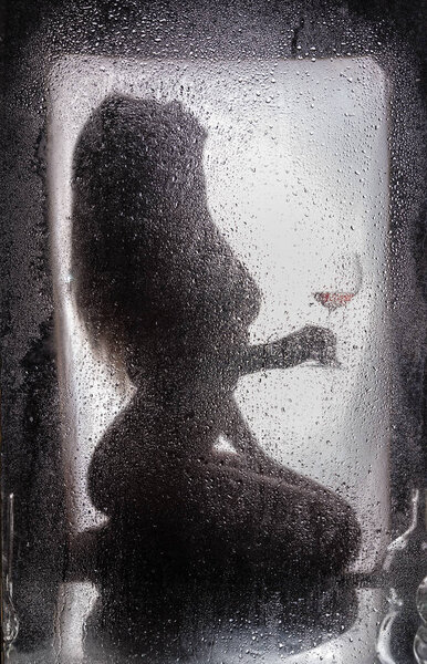 Naked girl behind a wet glass