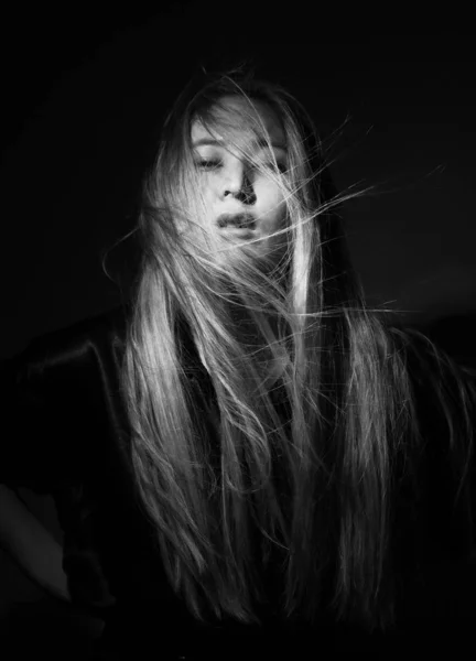 Portrait of a blonde in black clothes on a black background.