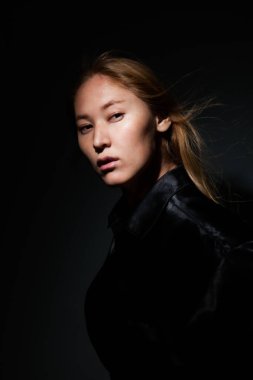 Siyah arka planda siyah elbiseli bir sarışın portresi..