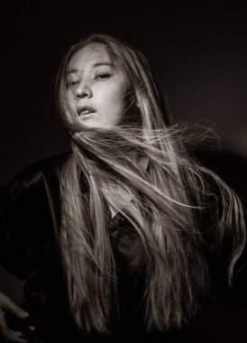 Siyah arka planda siyah elbiseli bir sarışın portresi..