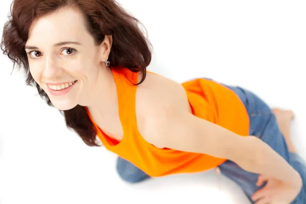 Een Meisje Jeans Een Oranje Shirt Zit Een Witte Achtergrond — Stockfoto