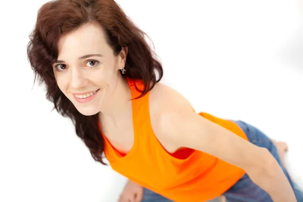 Ein Mädchen Jeans Und Orangefarbenem Shirt Sitzt Auf Weißem Hintergrund — Stockfoto