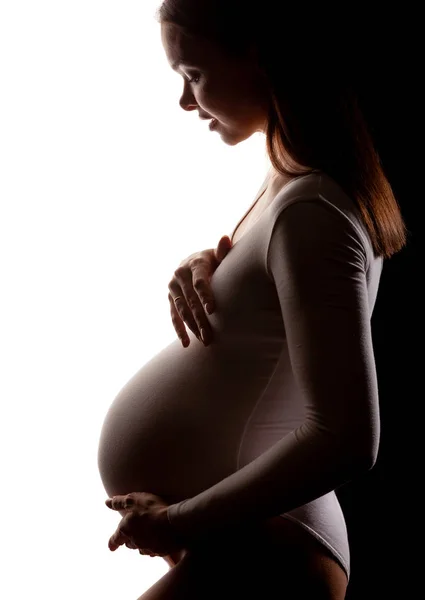 Pregnant woman in a white bodysuit on a white and black background.